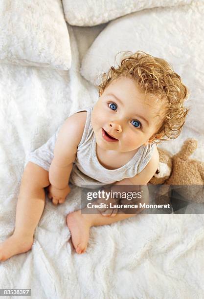 smiling toddler raising head sat on white blanket - cute baby stockfoto's en -beelden
