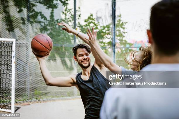 basketball players competing for control of the ball during afternoon match - young man holding basketball stockfoto's en -beelden