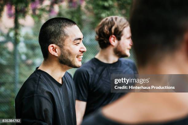 young man smiling as he discusses game strategy with team mates - só homens jovens imagens e fotografias de stock