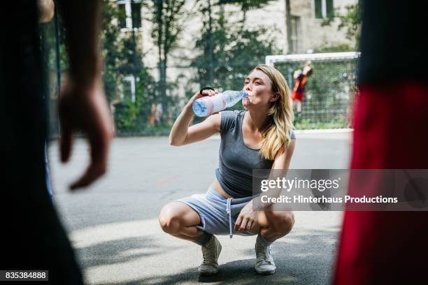 young woman taking break from basketball game to drink water - drink water fotografías e imágenes de stock