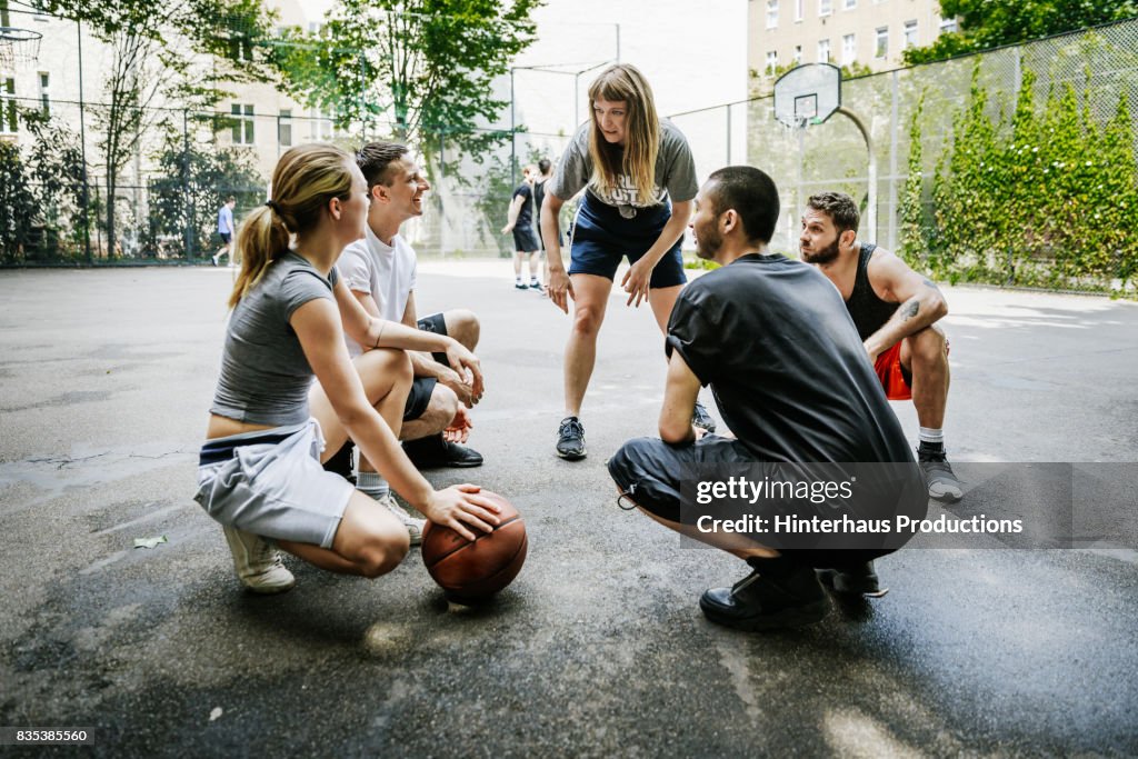 Group Of Friends Huddled Together Talking About Basketball Tactics.