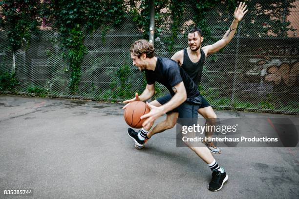 two young urban basketball players battling for control of the ball - basketball sport stock-fotos und bilder