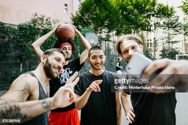 group of urban basketball players taking selfie together - young man holding basketball stockfoto's en -beelden