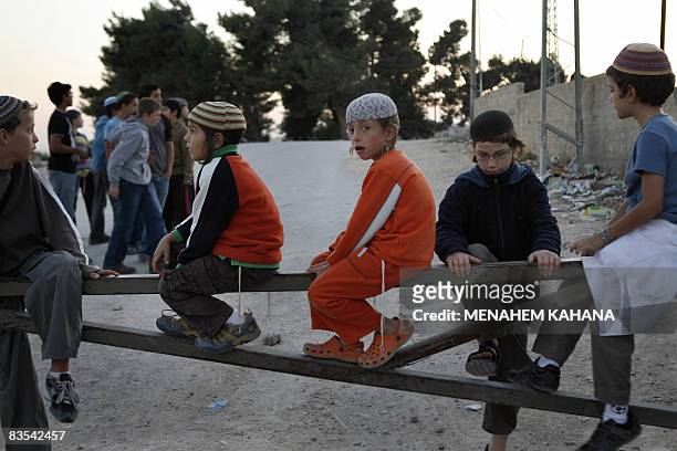 Children of Israeli settlers play on the gate of a checkpoint near a Palestinian house occupied by settlers in the West Bank city of Hebron on...