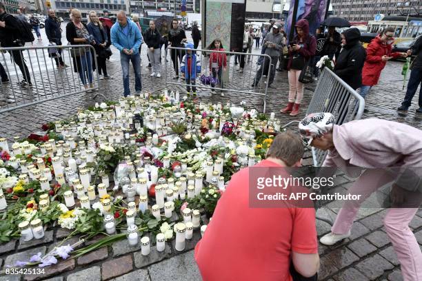 Peopole lay candles and flowers at the makeshift memorial for the victims of Friday's stabbings at the Turku Market Square, Finland on August 19,...