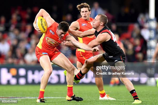 Suns player Pearce Hanley is caught by the defence of James Kelly of the Bombers during the round 22 AFL match between the Gold Coast Suns and the...