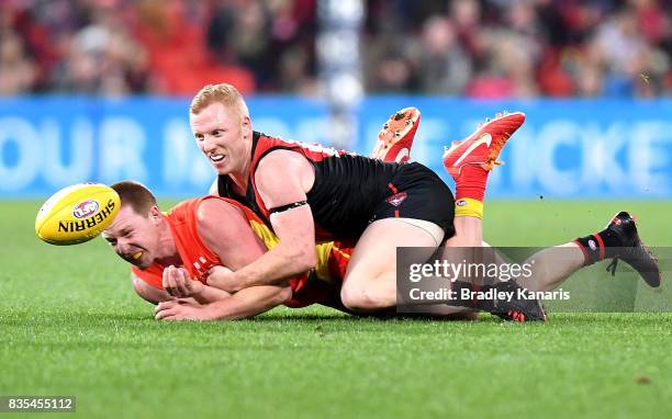 Jesse Joyce of the Suns is tackled by Josh Green of the Bombers during the round 22 AFL match between the Gold Coast Suns and the Essendon Bombers at...