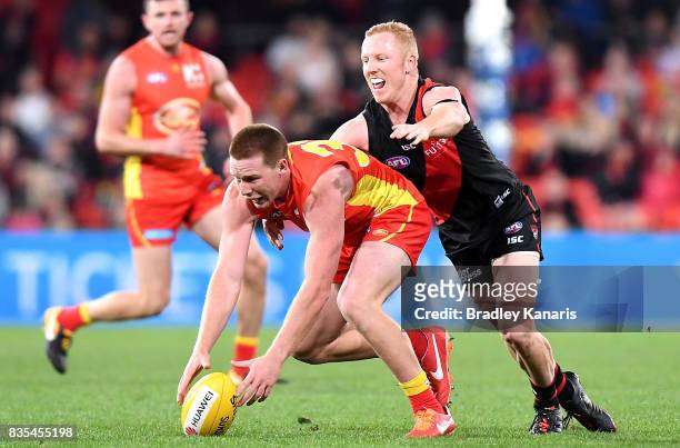 Jesse Joyce of the Suns is tackled by Josh Green of the Bombers during the round 22 AFL match between the Gold Coast Suns and the Essendon Bombers at...