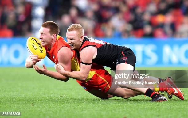 Jesse Joyce of the Suns is tackled by Josh Green of the Bombers during the round 22 AFL match between the Gold Coast Suns and the Essendon Bombers at...