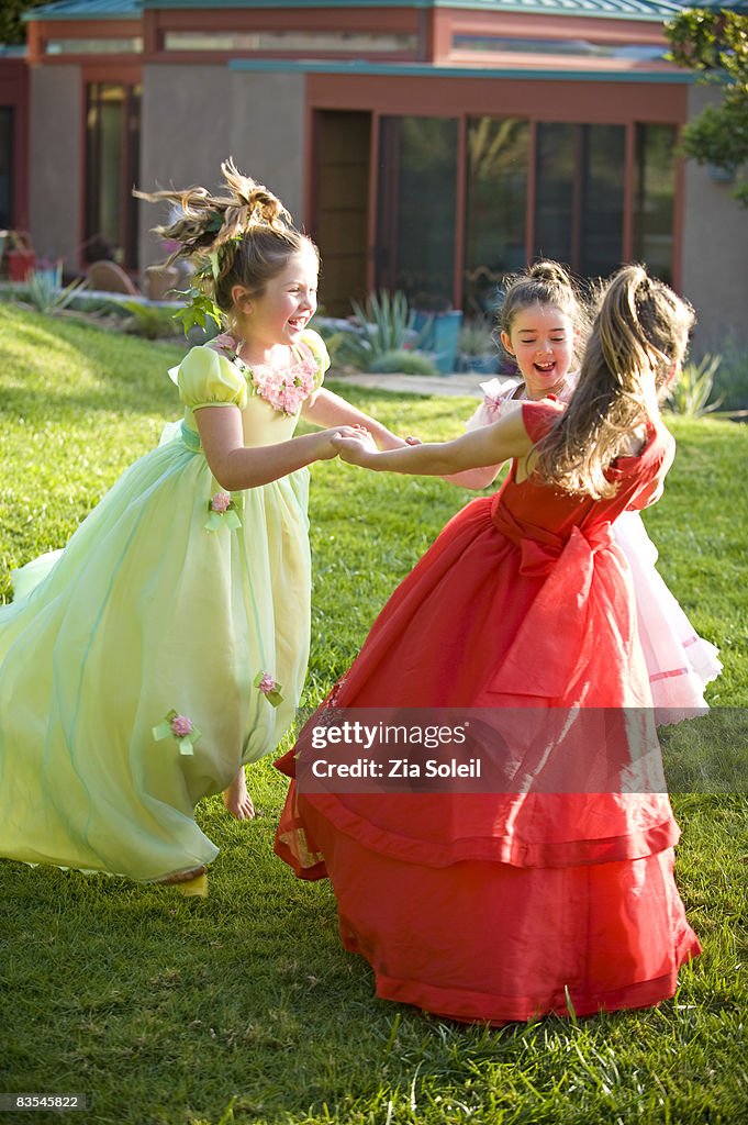 Girls in fancy dresses dancing in backyard