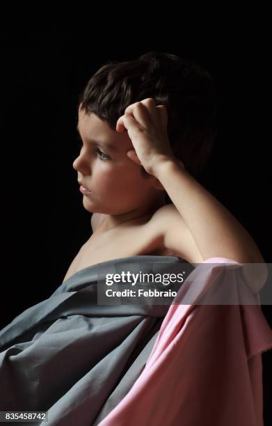 portrait of boy covered with gray and pink cloths with hand in his head - clair obscur stockfoto's en -beelden