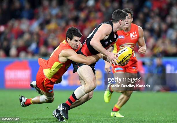 Conor McKenna of the Bombers is pressured by the defence of Matt Rosa of the Suns during the round 22 AFL match between the Gold Coast Suns and the...