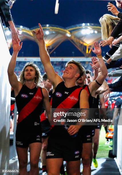 Joshua Begley of the Bombers celebrates with team mates after victory during the round 22 AFL match between the Gold Coast Suns and the Essendon...