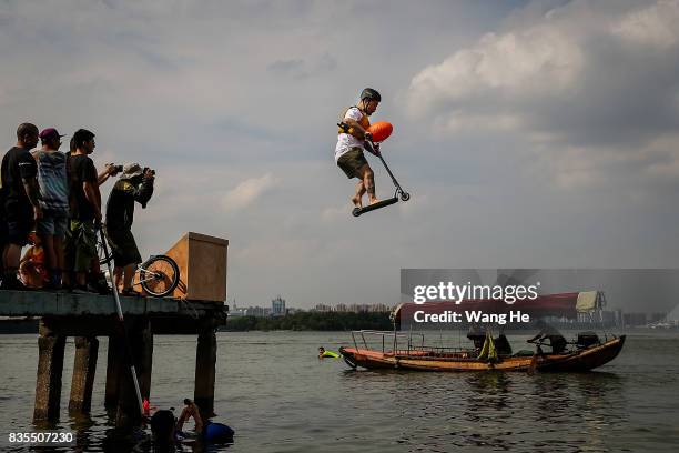 An extreme cycling enthusiast performs a stunt with a bicycle before falling into the East Lake on August 19, 2017 in Wuhan, Hubei province, China....