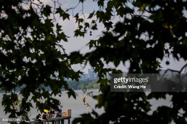 An extreme cycling enthusiast performs a stunt with a bicycle before falling into the East Lake on August 19, 2017 in Wuhan, Hubei province, China....