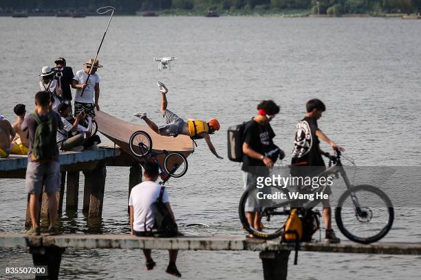 An extreme cycling enthusiast riding a bicycle falls into the East Lake on August 19, 2017 in Wuhan, Hubei province, China. This activity, which...