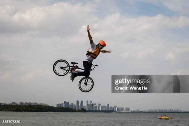 An extreme cycling enthusiast performs a stunt with a bicycle before falling into the East Lake on August 19, 2017 in Wuhan, Hubei province, China....