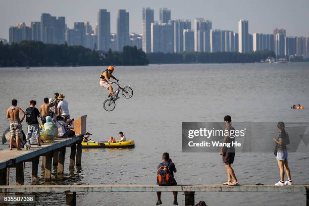 An extreme cycling enthusiast performs a stunt with a bicycle before falling into the East Lake on August 19, 2017 in Wuhan, Hubei province, China....