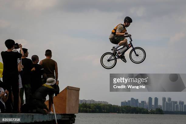 An extreme cycling enthusiast performs a stunt with a bicycle before falling into the East Lake on August 19, 2017 in Wuhan, Hubei province, China....