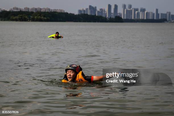 An extreme cycling enthusiast swims ashore after he performs a stunt with a bicycle into the East Lake on August 19, 2017 in Wuhan, Hubei province,...