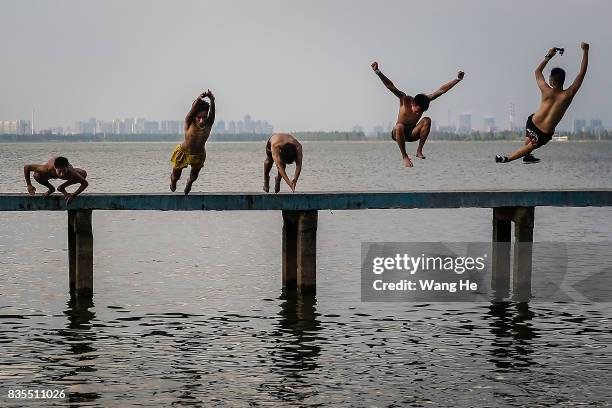 Residents jump into East Lake on August 19, 2017 in Wuhan, Hubei province, China. This activity, which requires participants to ride their bikes and...