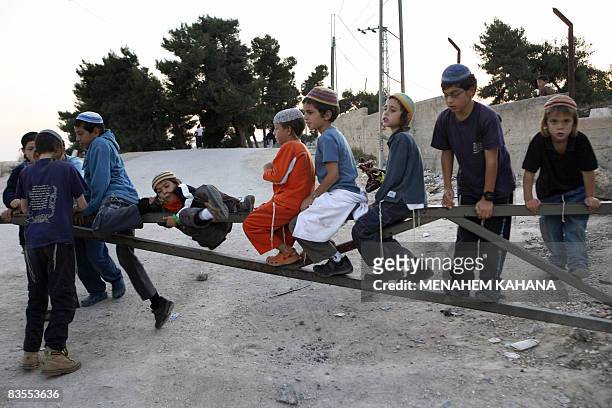 Children of Israeli settlers play on the gate of a checkpoint near a Palestinian house occupied by settlers in the West Bank city of Hebron on...