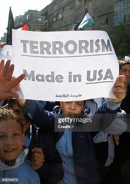 Palestinian school boys hold up anti-US slogans as they demonstrate against the United States' latest attack on Syria in the Palestinian al-Yarmuk...