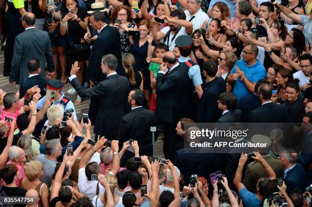 Spain's King Felipe VI and Spain's Queen Letizia wave as they leave after paying tribute to the victims of the Barcelona attack on Las Ramblas...