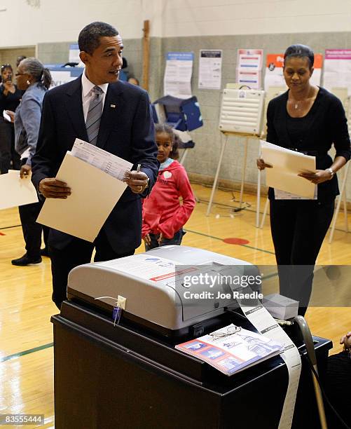 Democratic presidential nominee U.S. Sen. Barack Obama his wife Michelle and daughter Sasha carry their ballots to the vote tabulation machine...