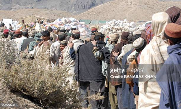 Pakistani earthquake survivors lineup as they wait for relief supplies at a hilly area of Wam, one of about eight sparsely populated villages...