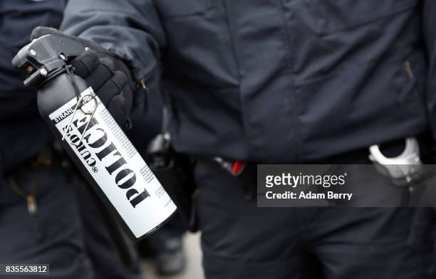 Police officer protectively holds a pepper gas canister as Neo-Nazis march at an extreme right-wing demonstration commemorating the 30th anniversary...