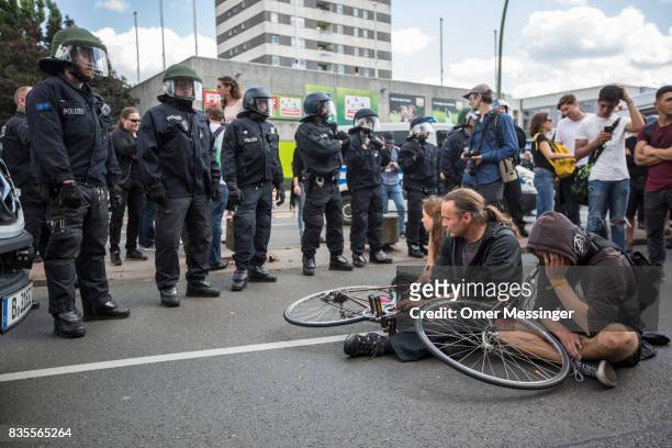 Counter demonstrators sit on the road in order to block a Neo-Nazi march as German riot police form a line in front of them, on August 19, 2017 in...