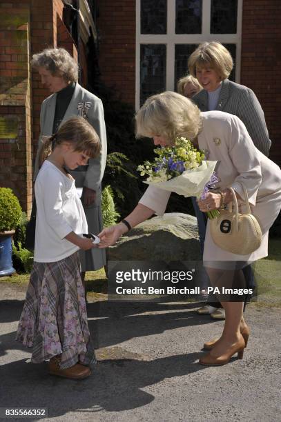 The Duchess of Cornwall accepts a posie from Ellen Coles, aged six from Oxford, during her visit to the Exmoor Pony Centre in Exmoor, Somerset.