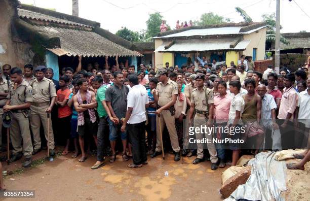 Villagers and onlookers stand near the spot of a crackers making unit explosion as rescue works going on at Siko village of Khorda district in the...