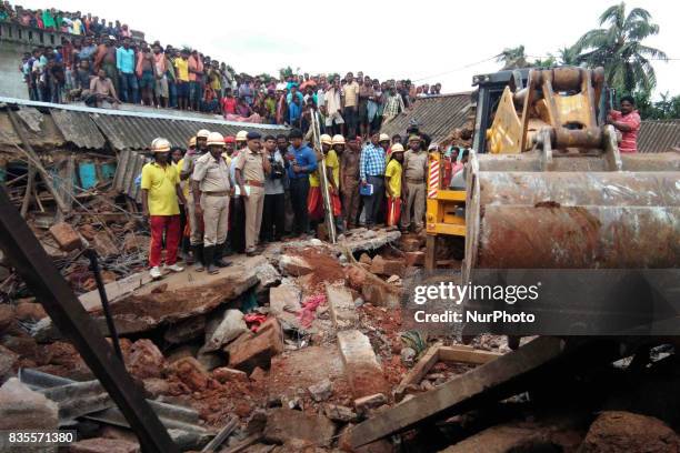 Villagers and onlookers stand near the spot of a crackers making unit explosion as rescue works going on at Siko village of Khorda district in the...