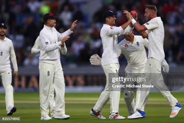 Stuart Broad of England celebrates with Alastair Cook after capturing the wicket of Jason Holder during day three of the 1st Investec Test match...