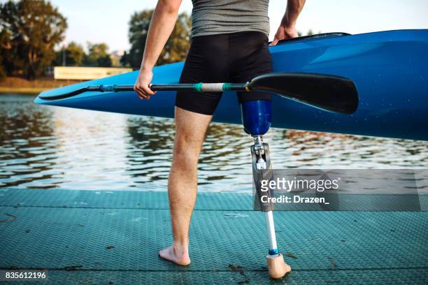 Differing ability athlete with artificial limb holding kayak