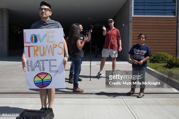 Steven Bibiano holds a sign while a young Trump supporter named Caeva watches during an anti-Trump demonstration outside of Google's offices on...