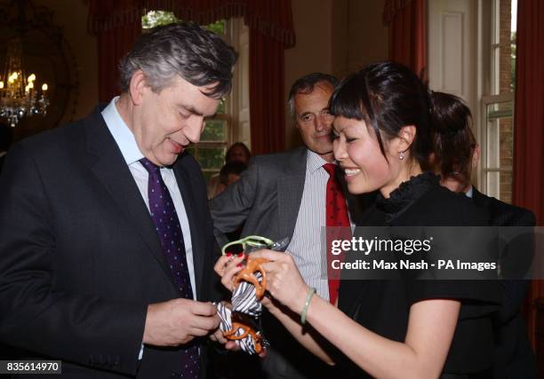 Julie Diem Le gives Prime Minister Gordon Brown two pairs of sunglasses for his children at a reception for entrepreneurs and business leaders at...