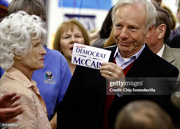 Sen. Joe Lieberman holds up a sticker that reads "Another Democrat for McCain" during a stop at a call center with Republican presidential nominee...