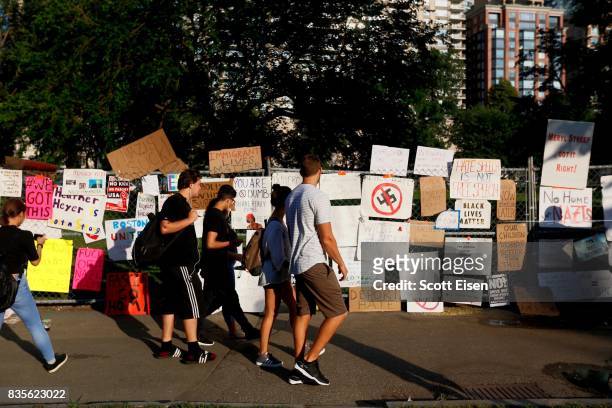 Onlookers check out a fence covered in signs from counter protesters following a march to a 'Free Speech Rally' on Boston Common on August 19, 2017...