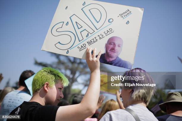 Elliot Schena, of Menlo Park, holds a sign poking fun at a man who was outed as a white nationaist after last week's rally in Charlottesville, at a...