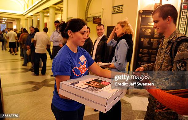 Maddie Potter a student at The University of Pittsburgh, passes out pizza as voters stand in line to cast a ballot during evening voting at a polling...