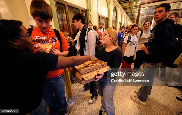 Jackie Hill a student at The University of Pittsburgh, passes out pizza as voters stand in line to cast a ballot during evening voting at a polling...