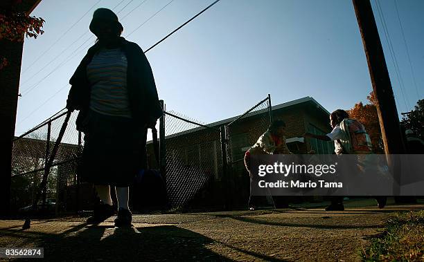 An African-American woman leaves after voting at a school as a young student runs during the presidential election November 4, 2008 in Birmingham,...