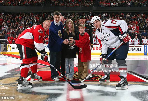 Daniel Alfredsson of the Ottawa Senators and Chris Clark of the Washington Capitals take a ceremonial faceoff with children of military personnel,...