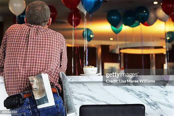 Man has a newspaper showing a photograph Senator John McCain in his pocket as he watches the US election results on tv at The American Club on...