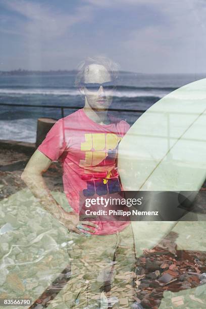 surfer with board behind window watching waves - philipp nemenz foto e immagini stock