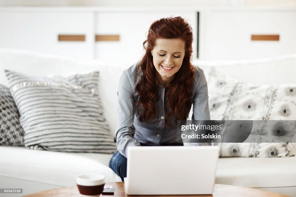 Woman sitting in sofa, using laptop