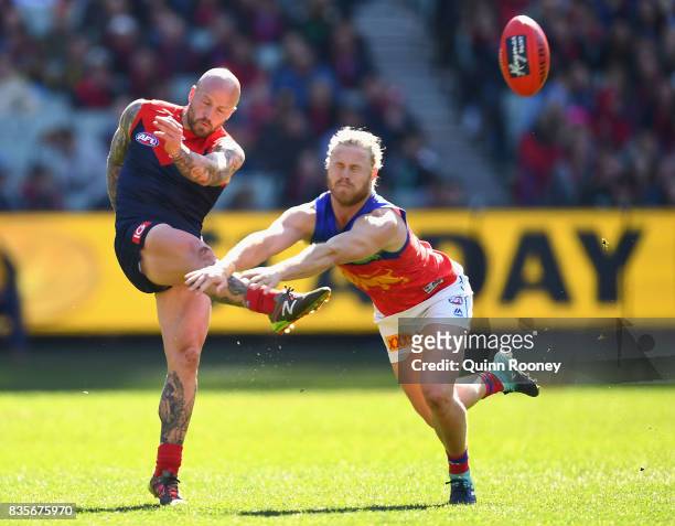 Nathan Jones of the Demons kicks whilst Daniel Rich of the Lions attempts to smouther during the round 22 AFL match between the Melbourne Demons and...